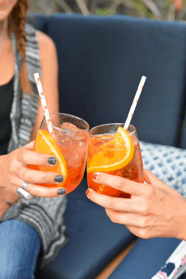 2 girls holding an Aperol Spritz and doing a cheers