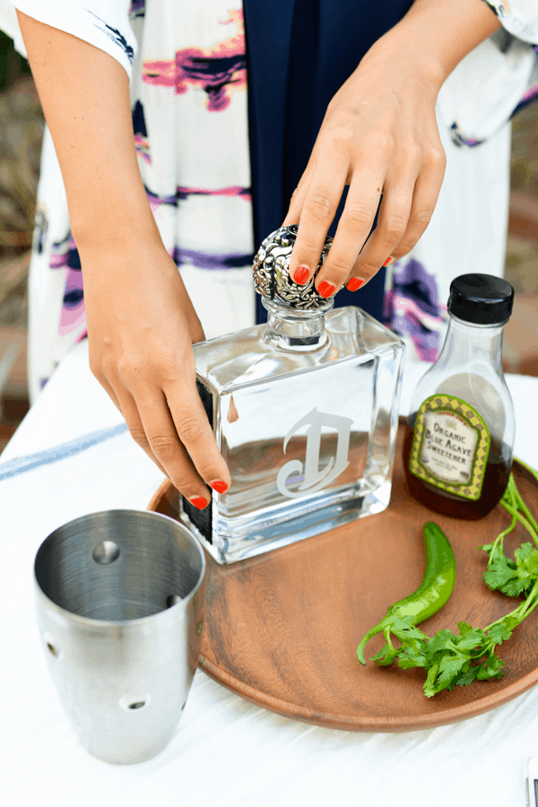 Woman opening a bottle of DeLeon tequila to make a spicy margarita..