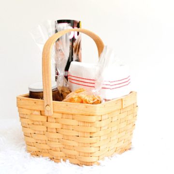 Close up of a basket with snacks and wine and a magazine to drop off for someone.