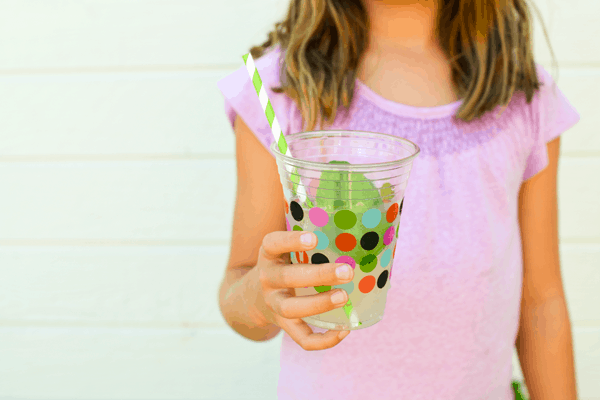 Girl holding a cup of lemonade with a straw. 