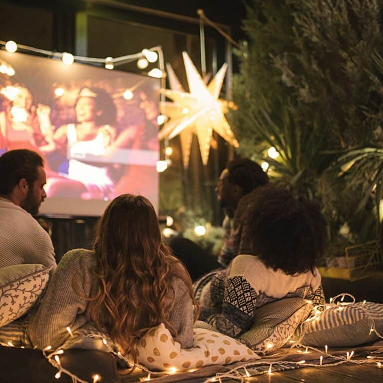 People on blankets watching an outdoor movie.