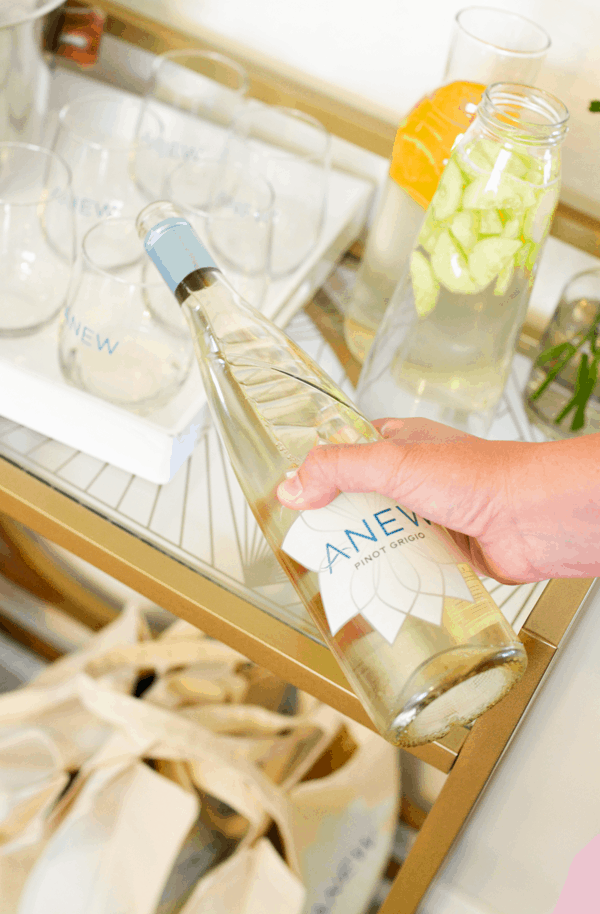 A woman pouring some wine into a stemless wine glass.