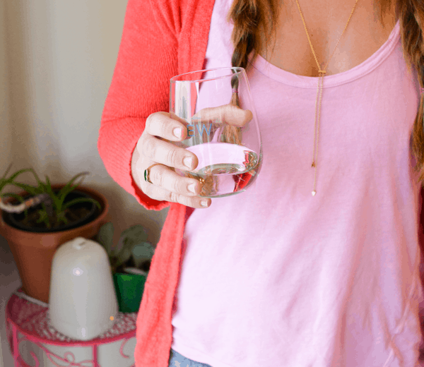 A woman holding a stemless wine glass with wine. 