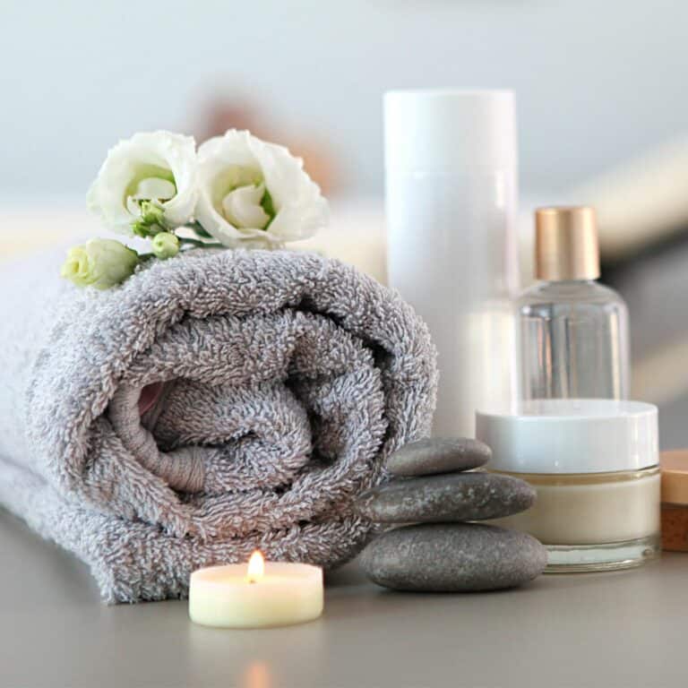 A rolled up towel in a spa setting with flowers and candles.