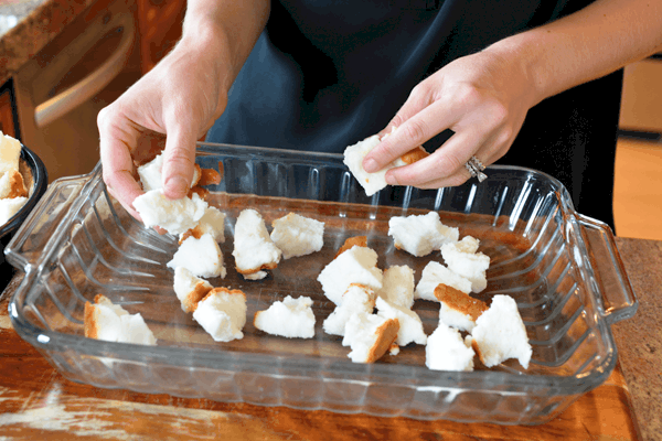 Girl putting chunks of angel food cake in to a baking dish for a strawberry dessert recipe.