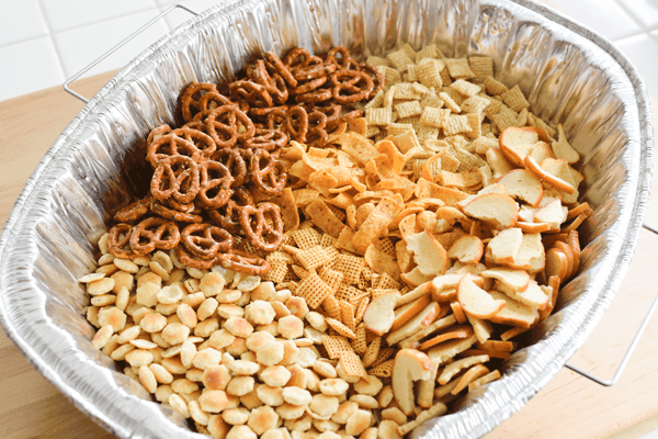 A disposable baking pan full of a variety of crunchy snacks. 