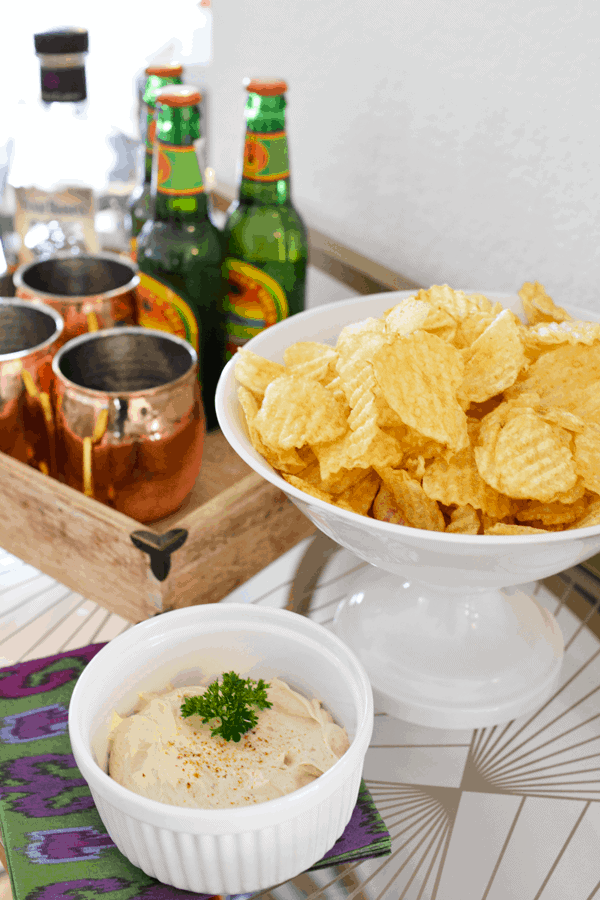 Chip and dip on a table next to a tray of Moscow Mules. 