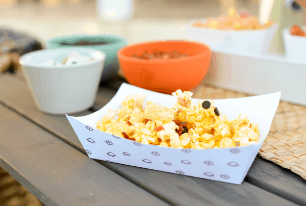 Close up of a homemade paper tray with popcorn and other toppings. 