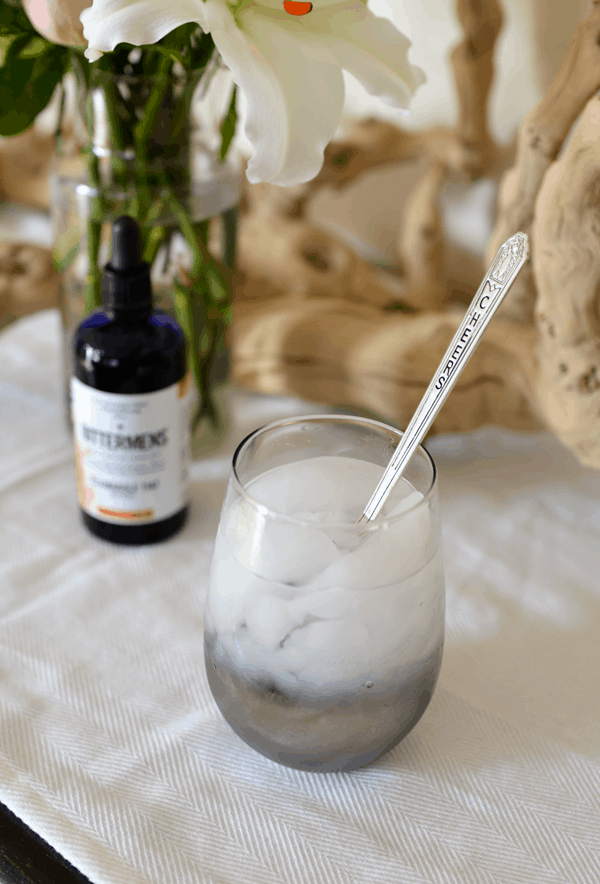 Close up of a stemless wine glass on a table with bitters behind it.