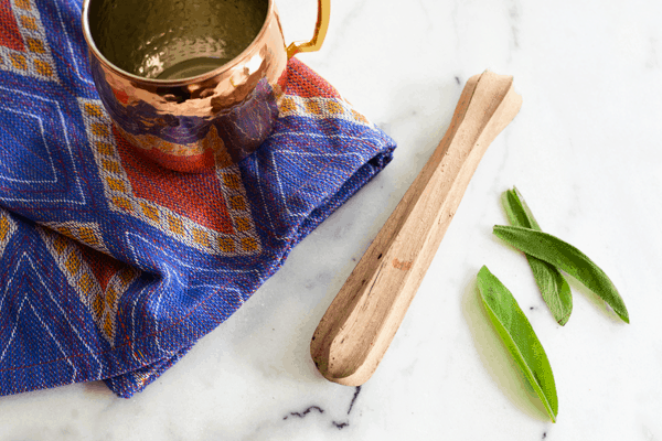 A copper mule mug and wooden muddler for making a Bourbon Mule recipe.