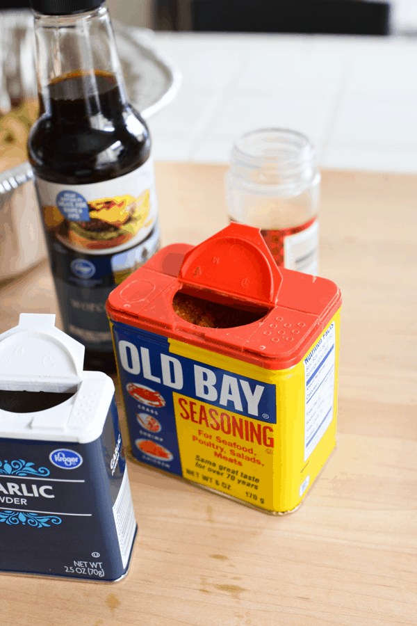 Close up of an open container of Old Bay Seasoning next to other spices and ingredients. 