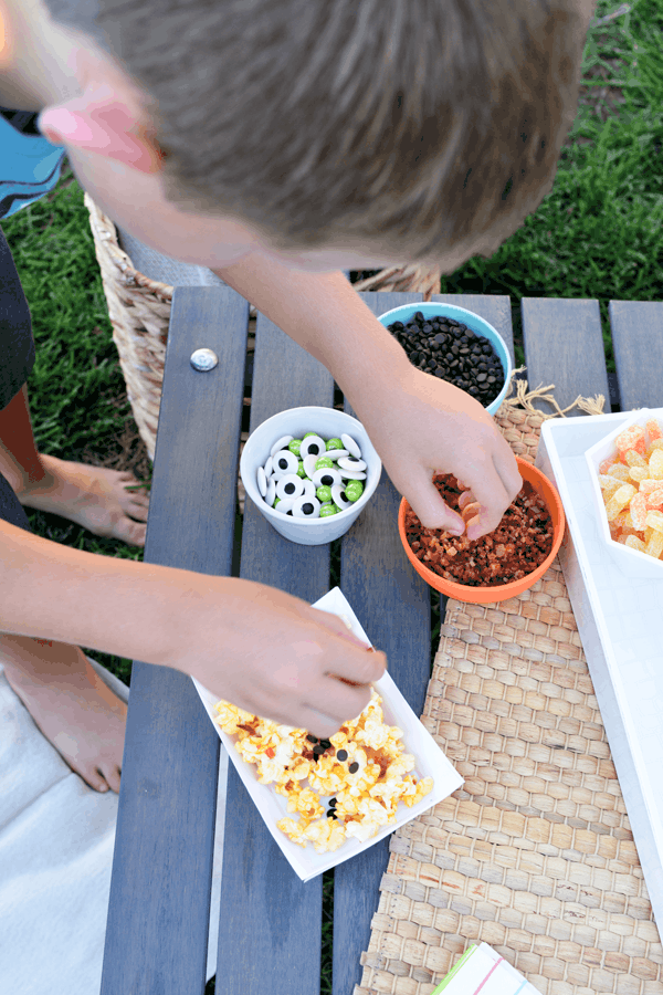 Boy putting snacks into a tray for an outdoor movie. 