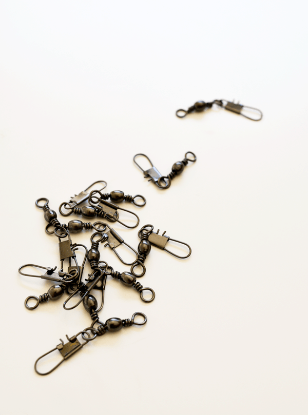 Snap swivels in a pile on a white table before using to make a homemade bracelet. 