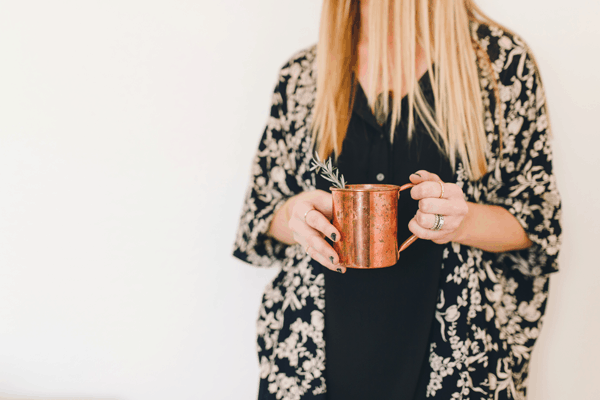 A woman holding a copper Moscow Mule mug. 