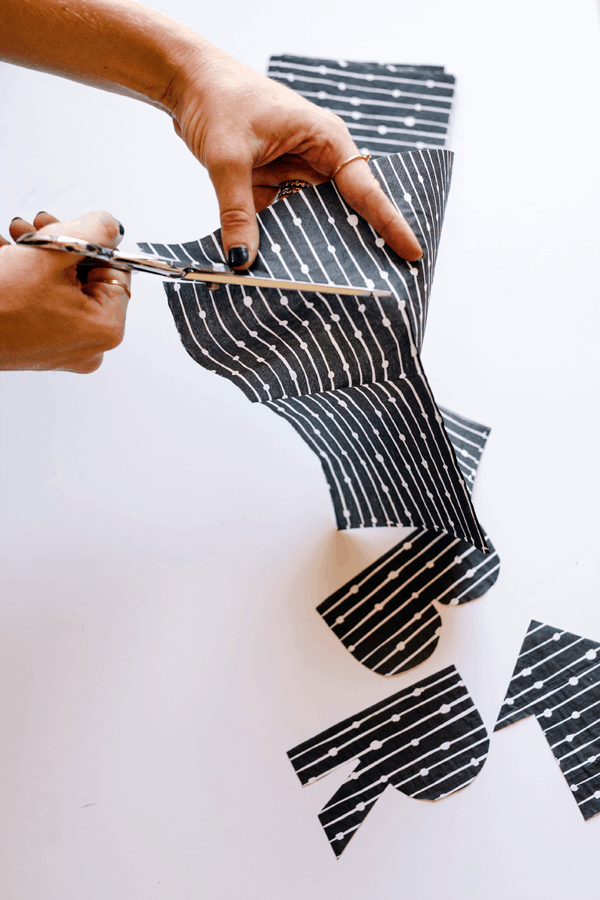 A woman cutting a paper napkin with scissors. 