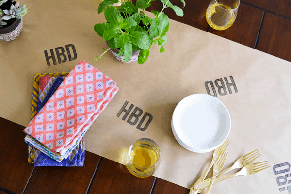 Make this easy birthday table runner! Use a store-bought stamp or a custom one for a personalized DIY party decoration. This could work for the holidays too! 