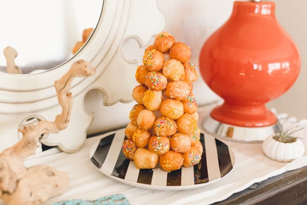 A donut hole tree on a table on a black and white stripe plate.