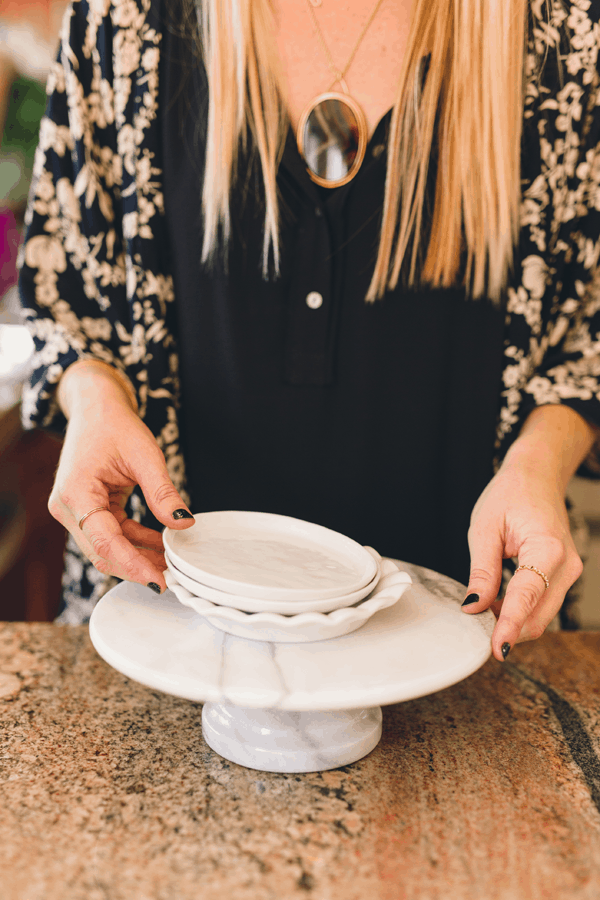 Woman setting small appetizer plates on top of a cake stand.