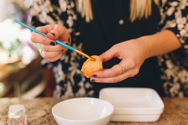 Woman holding a donut hole and painting it with a paintbrush.
