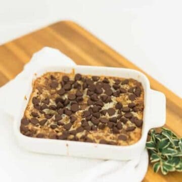 A small batch of old-fashioned 7 Layer Bars in a white dish on a wooden board.