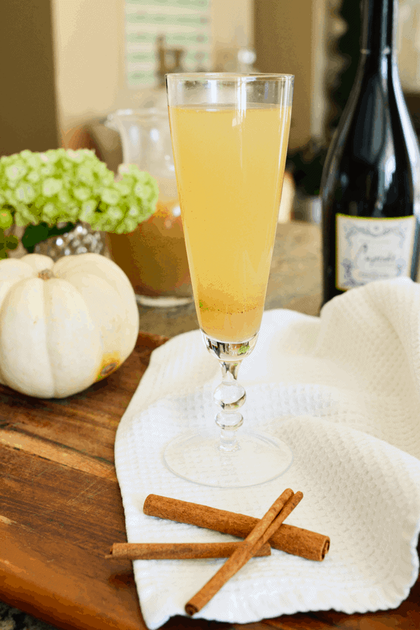 A wooden table topped with a champagne flute holding pear bellini.