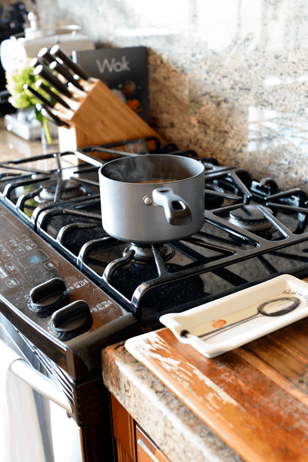 A sauce pan on a stove with something simmering inside.