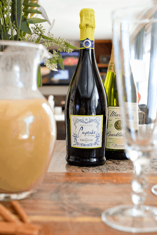 A bottle of Cupcake Vineyards Prosecco on a counter with cocktail ingredients around it.