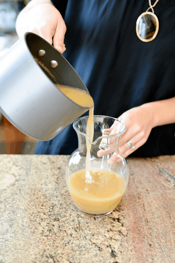 Woman pouring pear juice into a glass pitcher. 