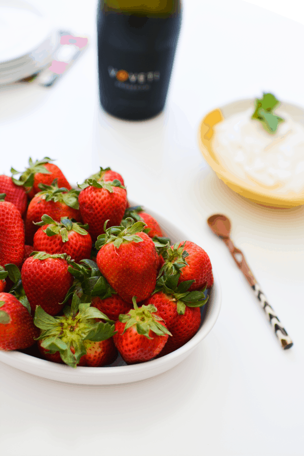 Fresh strawberries in a white bowl on a white table top.