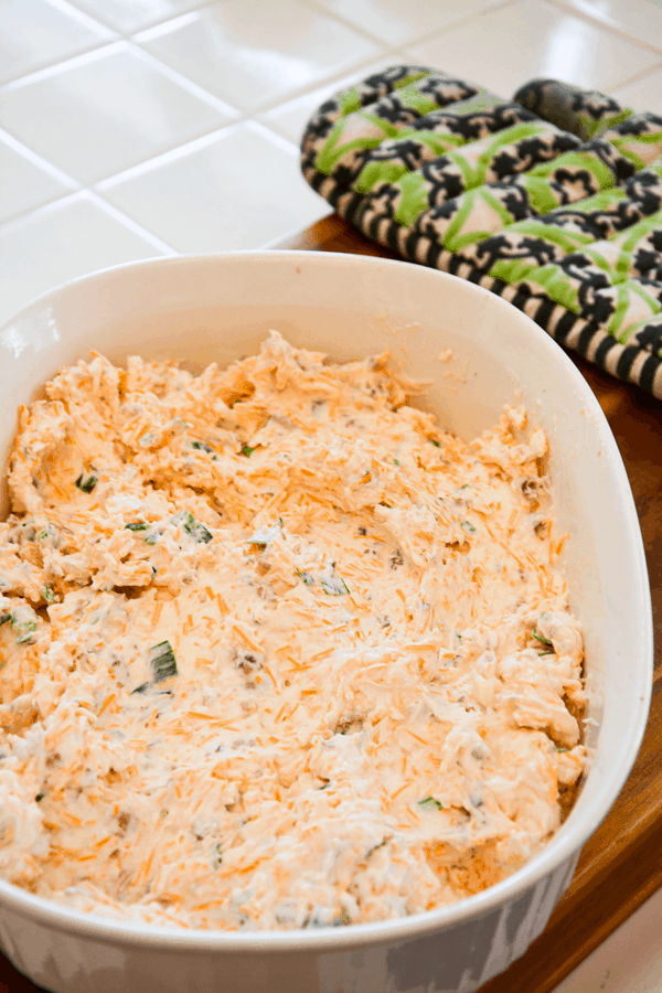 Baking dish on a cutting board with a cream cheese and cheddar cheese mixture. 