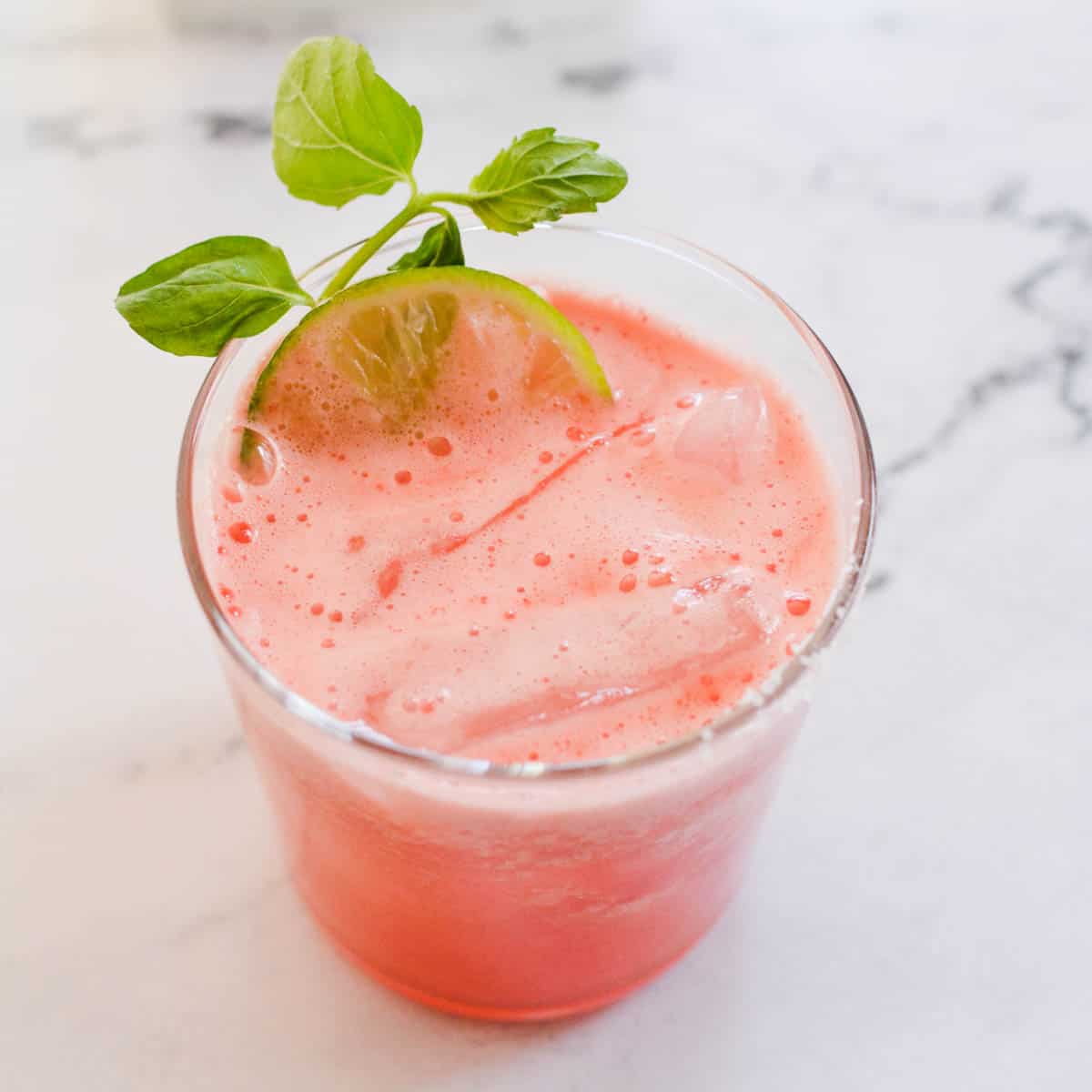 A fresh watermelon margarita in a short cocktail glass on the counter.