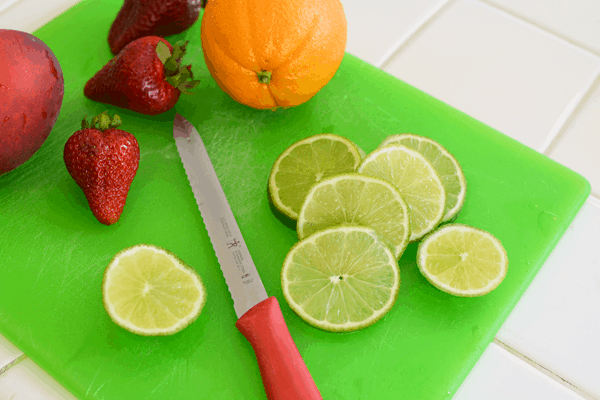 Fresh fruit being cut on a green cutting board.