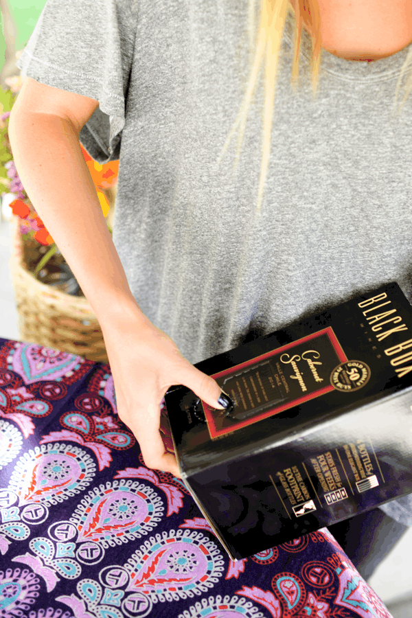 Woman picking up a box of wine.