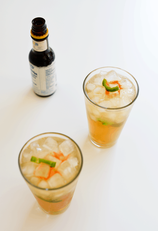 Mexican Mule Cocktails on a white countertop with a bottle of bitters in the background.