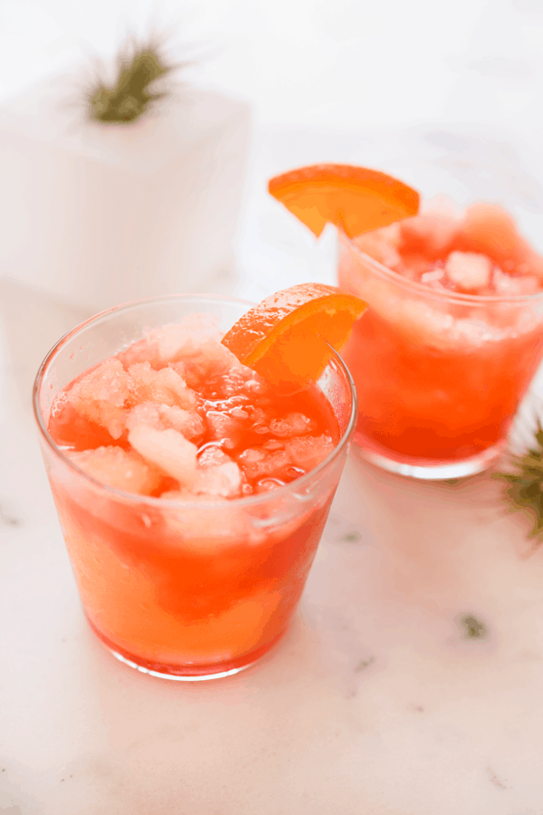 Slushie Vodka Sunrise cocktails served in glasses with an orange slice garnish. 