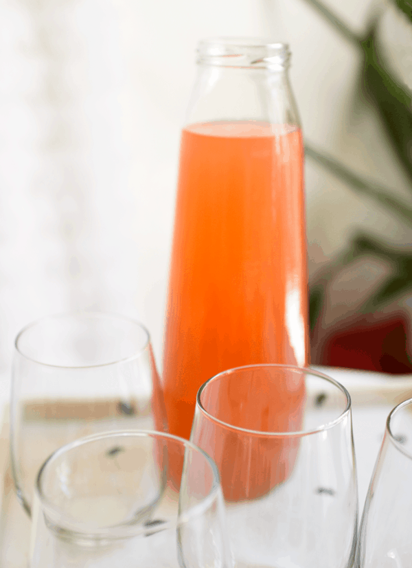 A bottle of strawberry lemonade and stemless wine glasses.