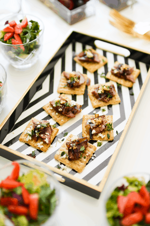 A tray of Blue Cheese topped Flank Steak Bites on Triscuits on a tray. 