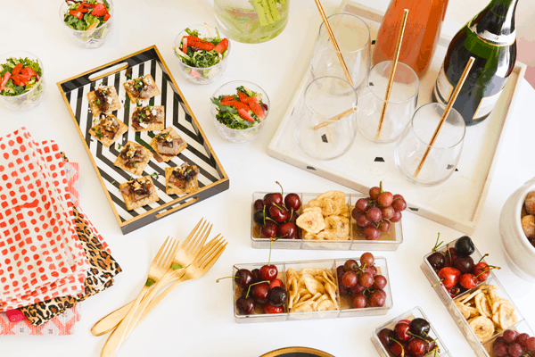 A variety of appetizers, snacks and cocktails on a white table top.