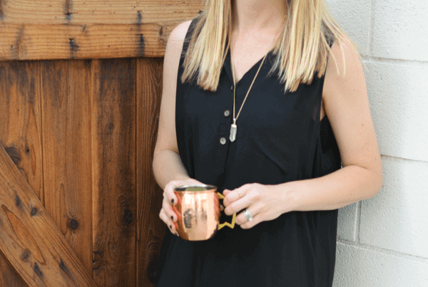 A woman holding a copper moscow mule mug with Absolut vodka mule.