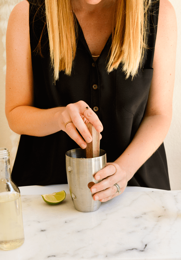 Woman muddling mint in a cocktail shaker. 