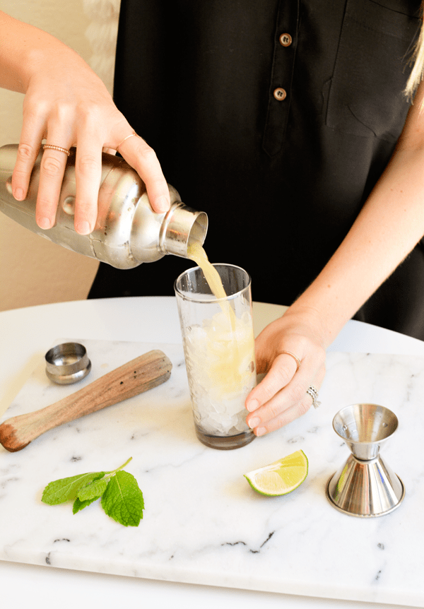 Pouring an apple mojito into a glass.