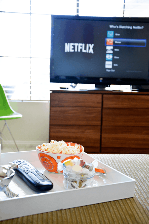 A tray of snacks on a couch with a TV out of focus in the background. 