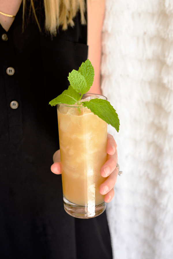 Woman holding a mojito made with apple juice with a mint garnish. 