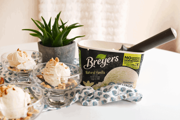 A fig dessert in bowls, next to a carton of ice cream on top of a blue and white kitchen towel.