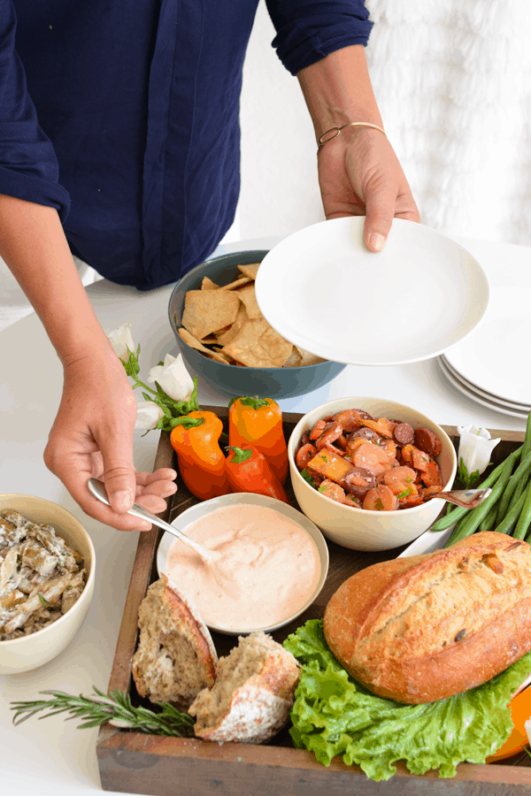 Woman spooning some dip onto an appetizer plate. 