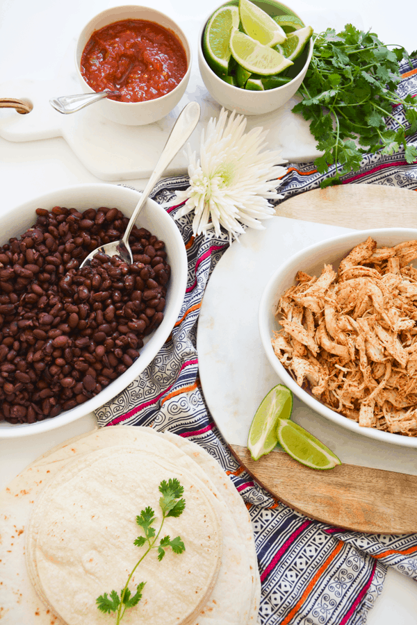 Serving bowls with beans and chicken on a table for taco night dinner. 