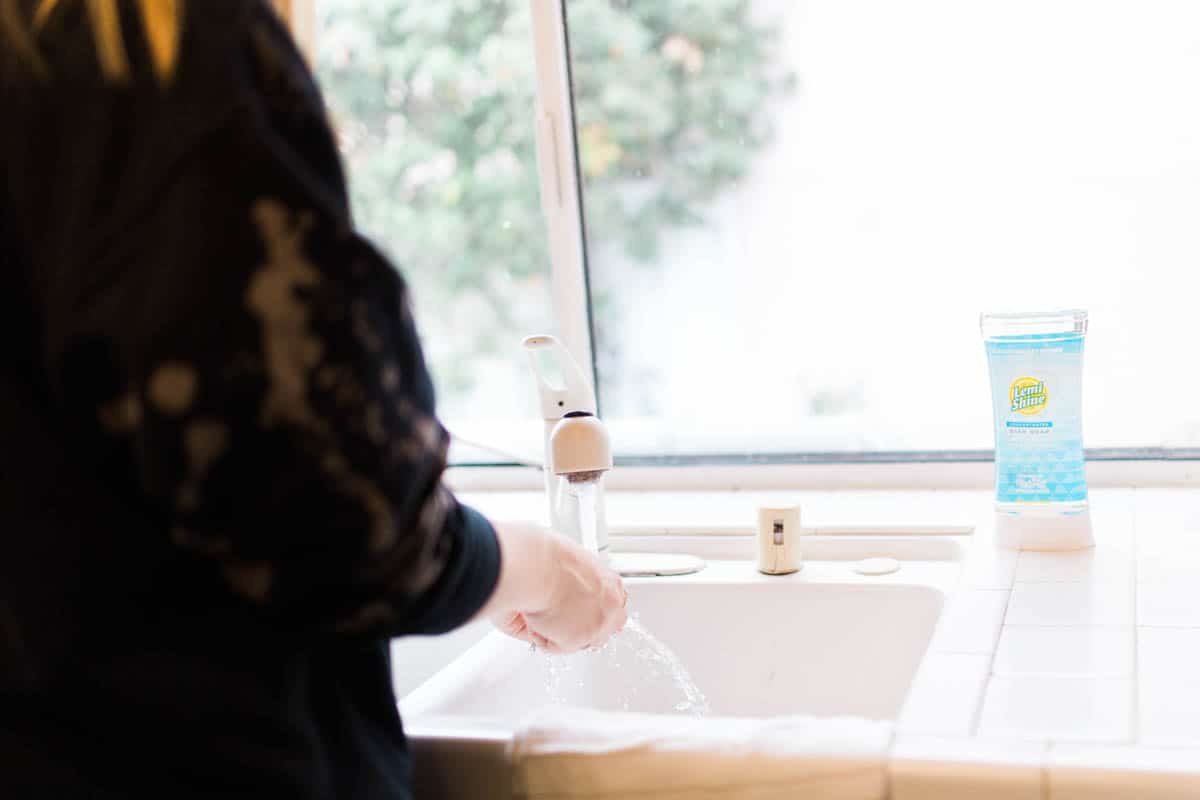 Woman cleaning a dish at the sink in the kitchen.