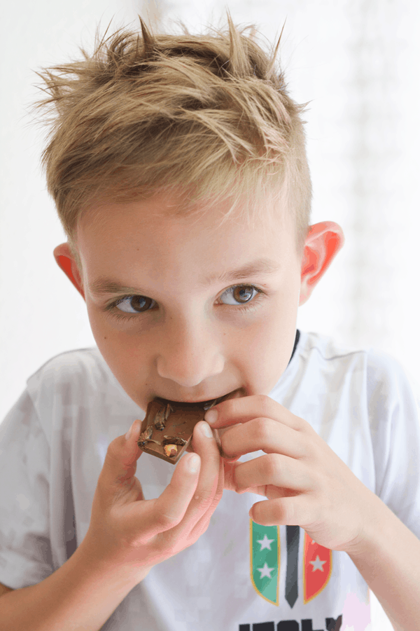 A young boy eating edible crickets on chocolate bark.