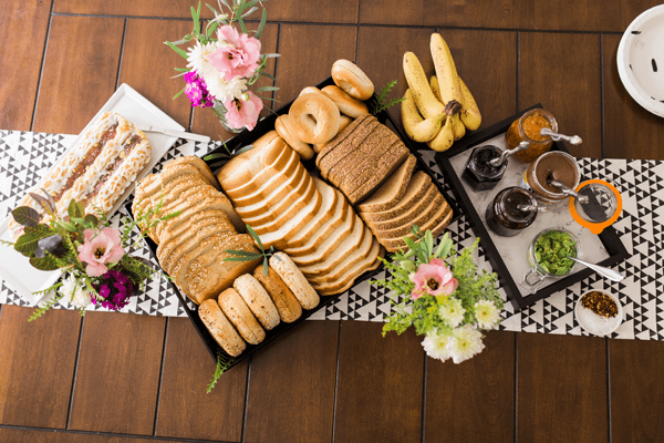 A breakfast table with a tray holding a variety of toasts and jams plus a danish for a brunch.