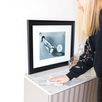 Woman in black sweatshirt cleaning a small marble topped table.
